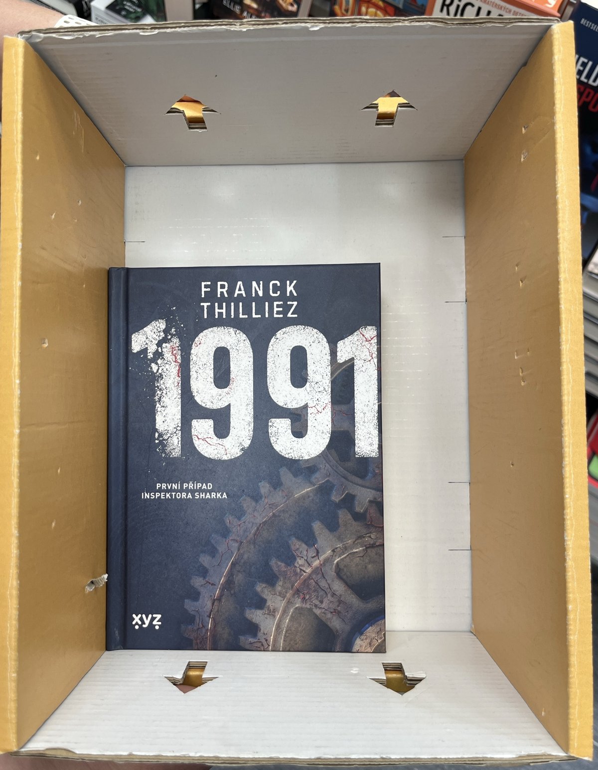 Prázdná krabice shora, na dně leží kniha 1991 od Francka Thillieze jako měřítko